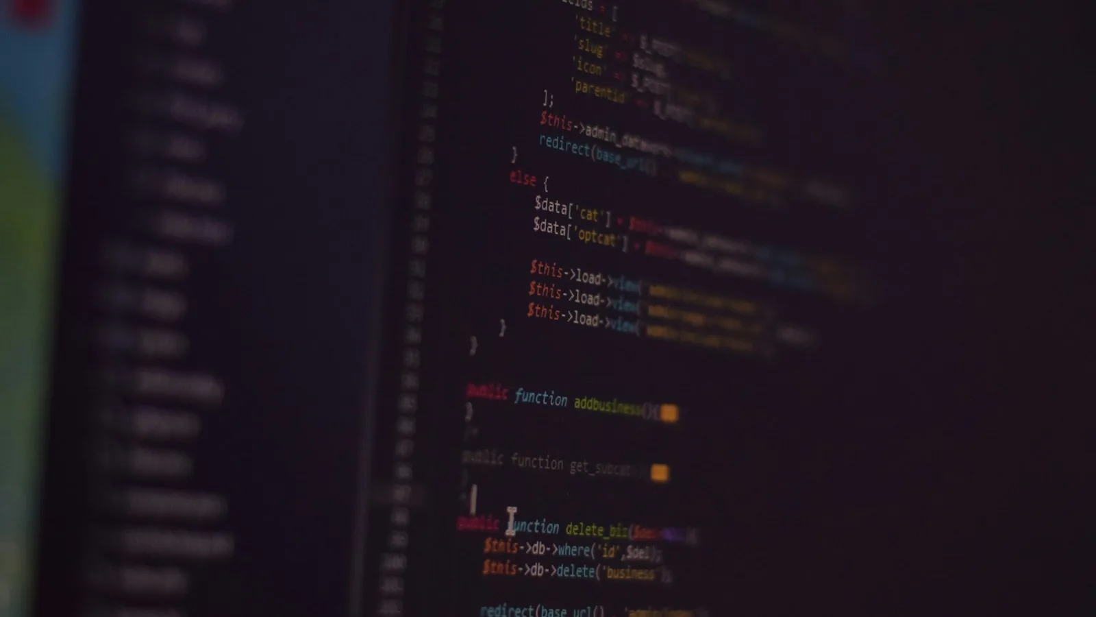 Primer plano borroso de una pantalla oscura con código PHP, funciones y llamadas de base de datos apenas legibles
